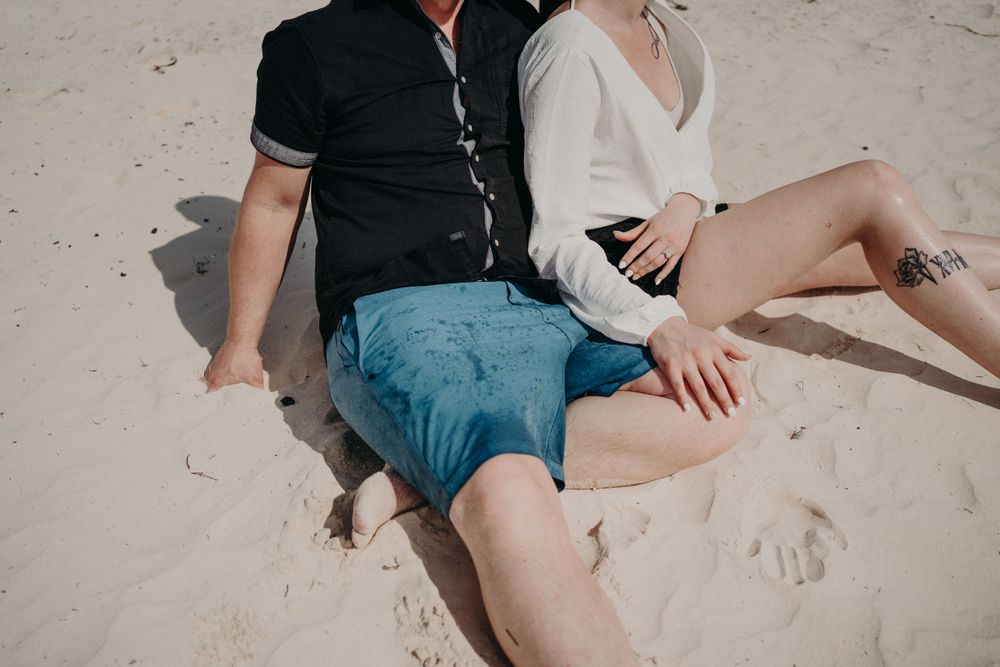A couple relaxing on sandy beach wearing contrasting black and white outfits photoshoot in Puerto Morelos.