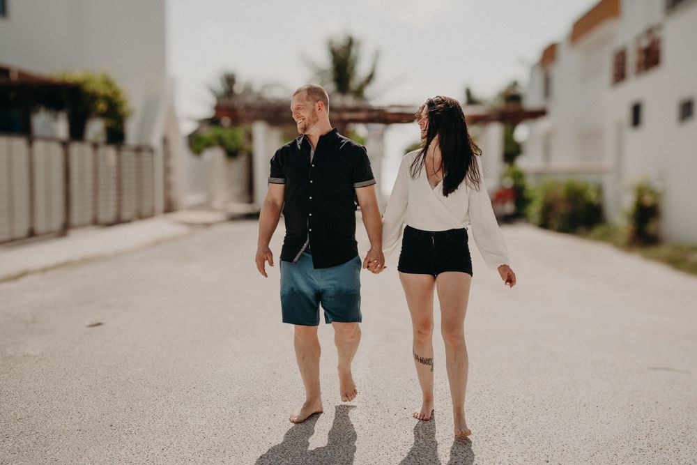 A couple walking hand in hand down a sunny residential street v