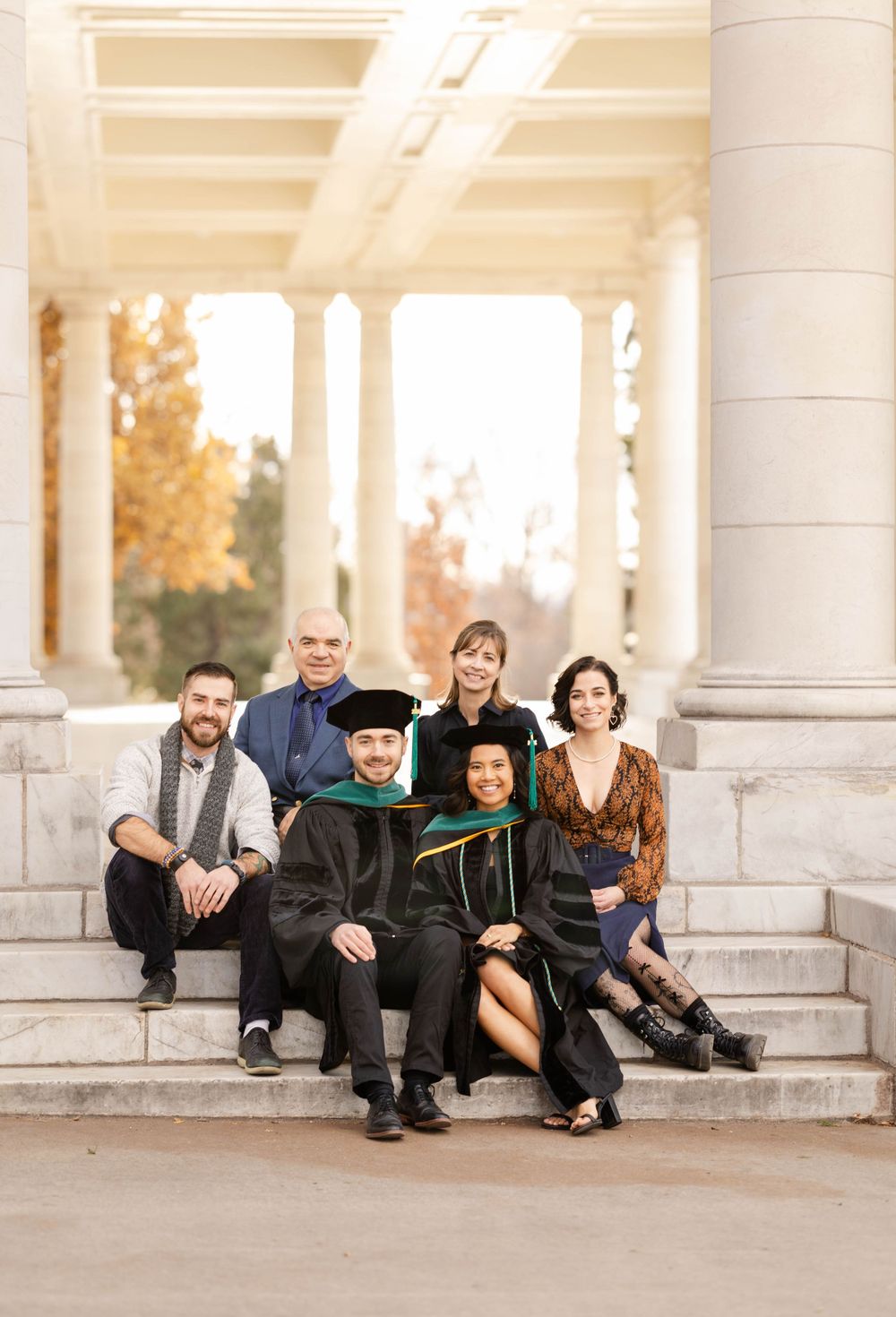 Extended family graduation photo on stone steps with classical architecture.