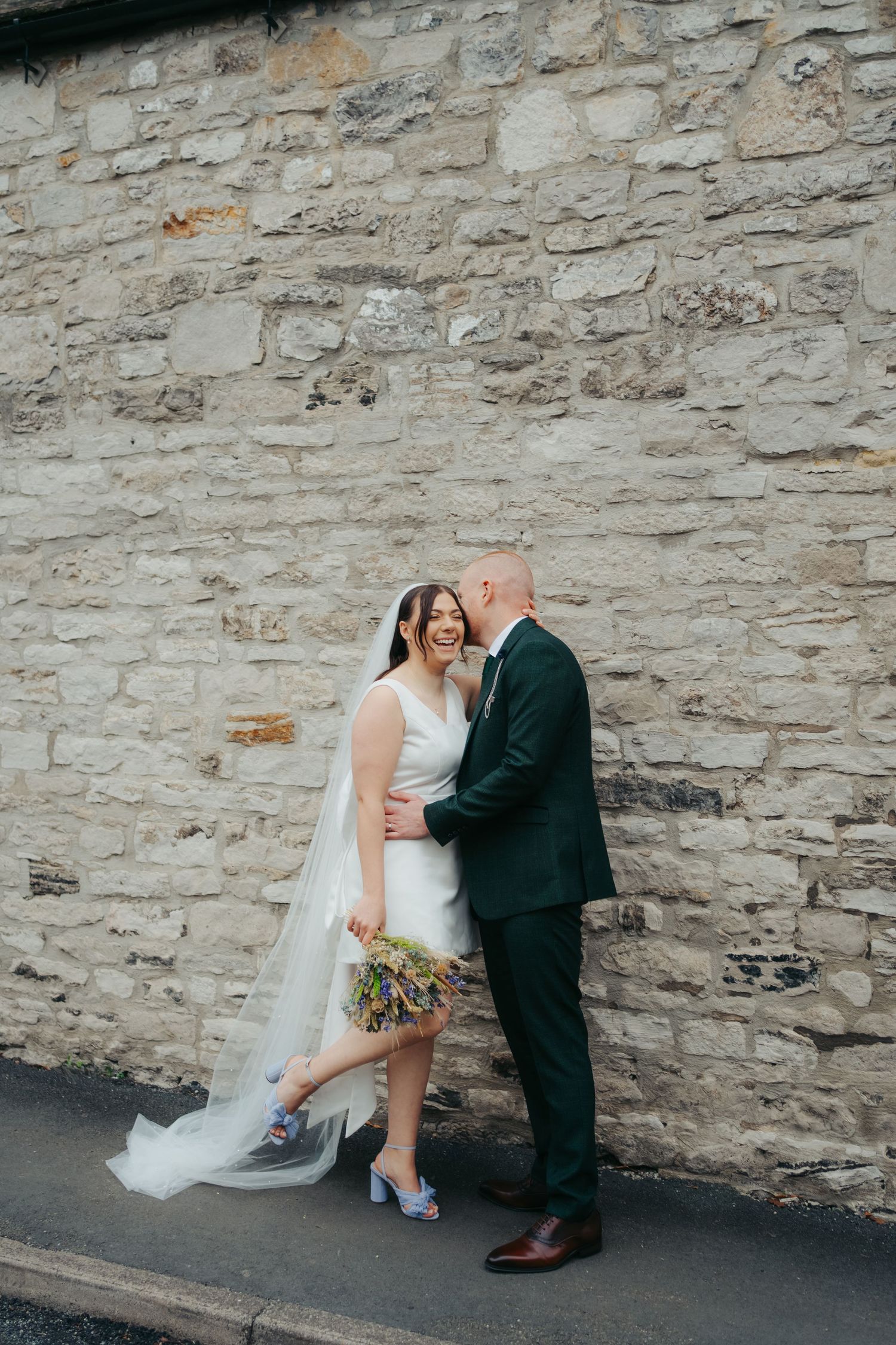 Groom kisses 1960s style bride as they exit small elopement ceremony in countryside village Bakewell