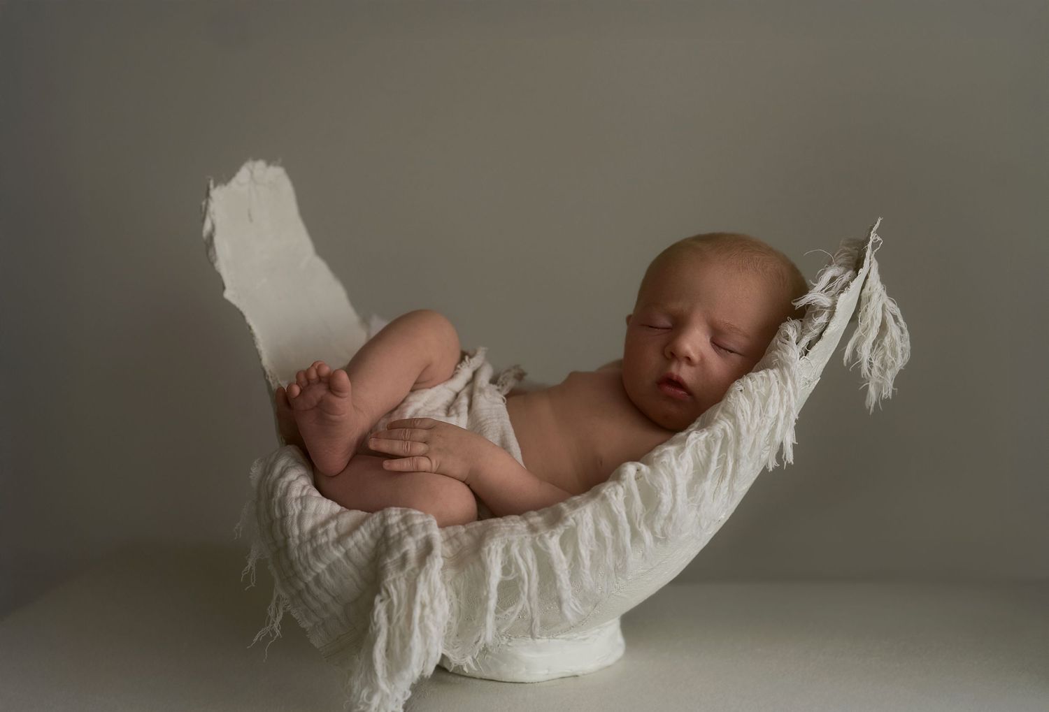 Sleeping newborn baby on star-patterned blanket wearing soft gray headband.