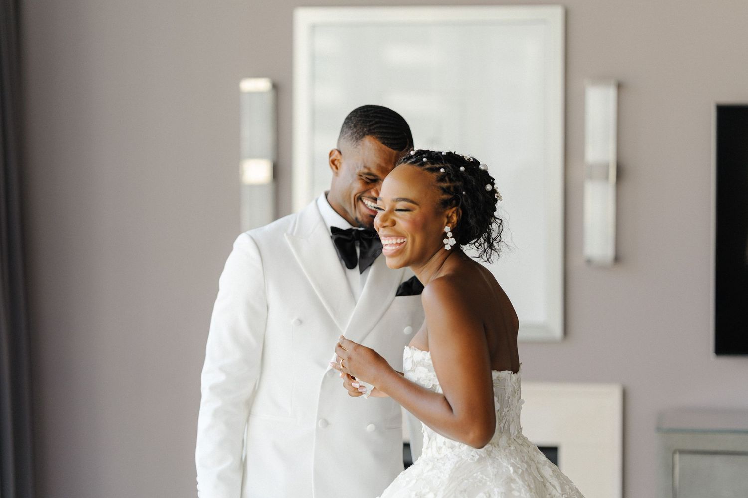 A joyful moment shared between a couple in elegant wedding attire in a modern setting.