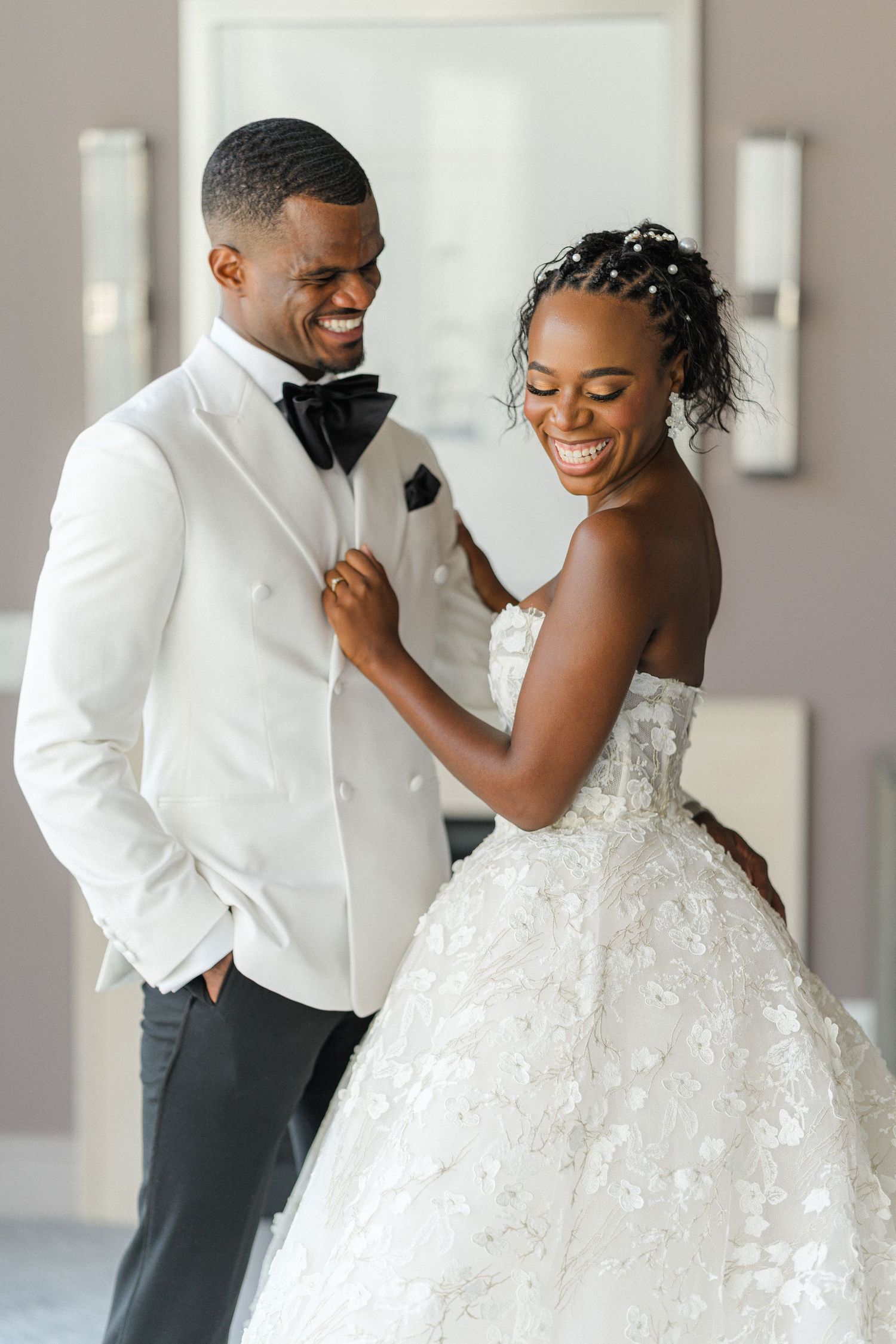 Happy couple sharing a joyful moment on their wedding day in elegant white attire.