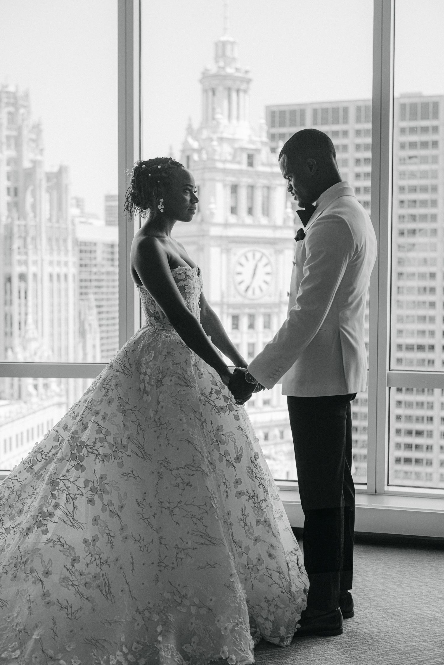 Silhouette of newlyweds holding hands against cityscape with historic architecture.