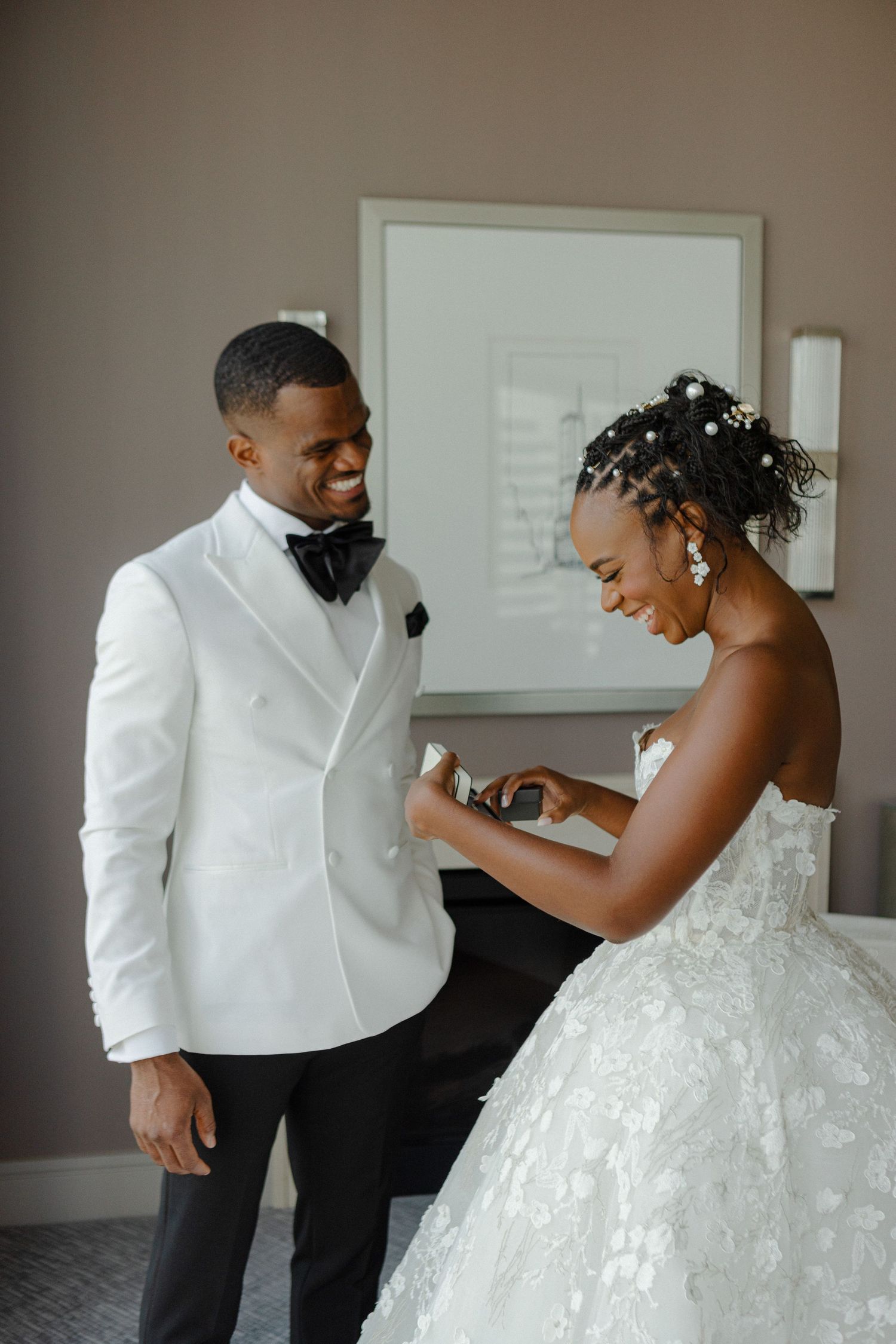 Playful wedding moment captured as bride adjusts groom's bow tie.