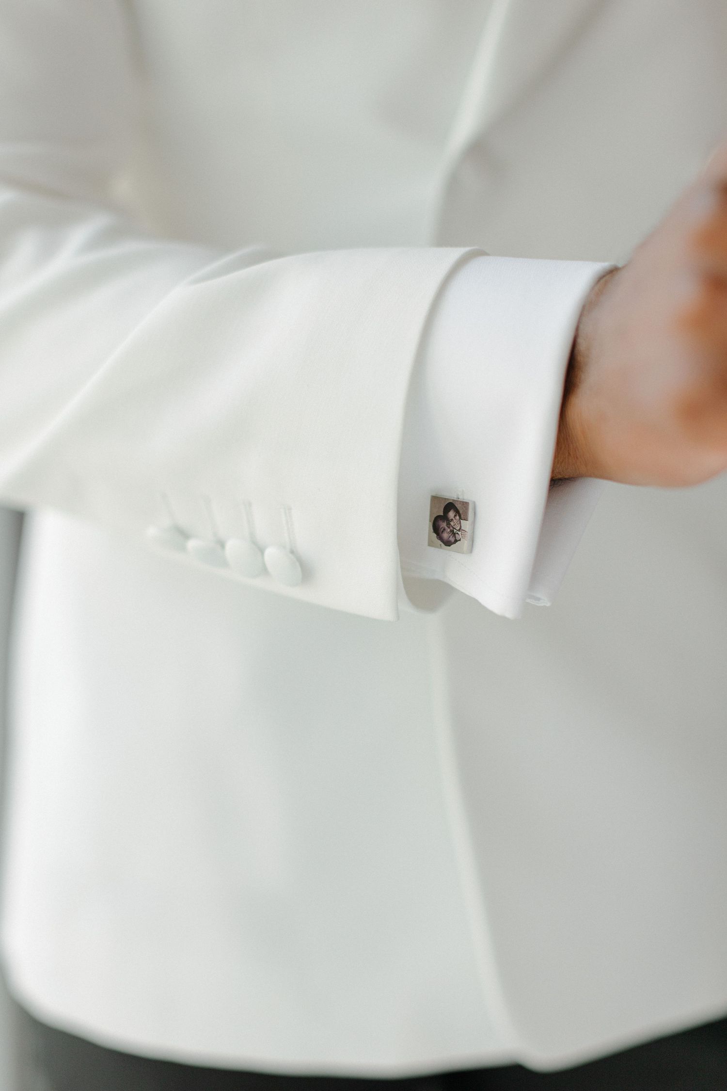 Detail shot of white tuxedo sleeve with elegant cufflink.