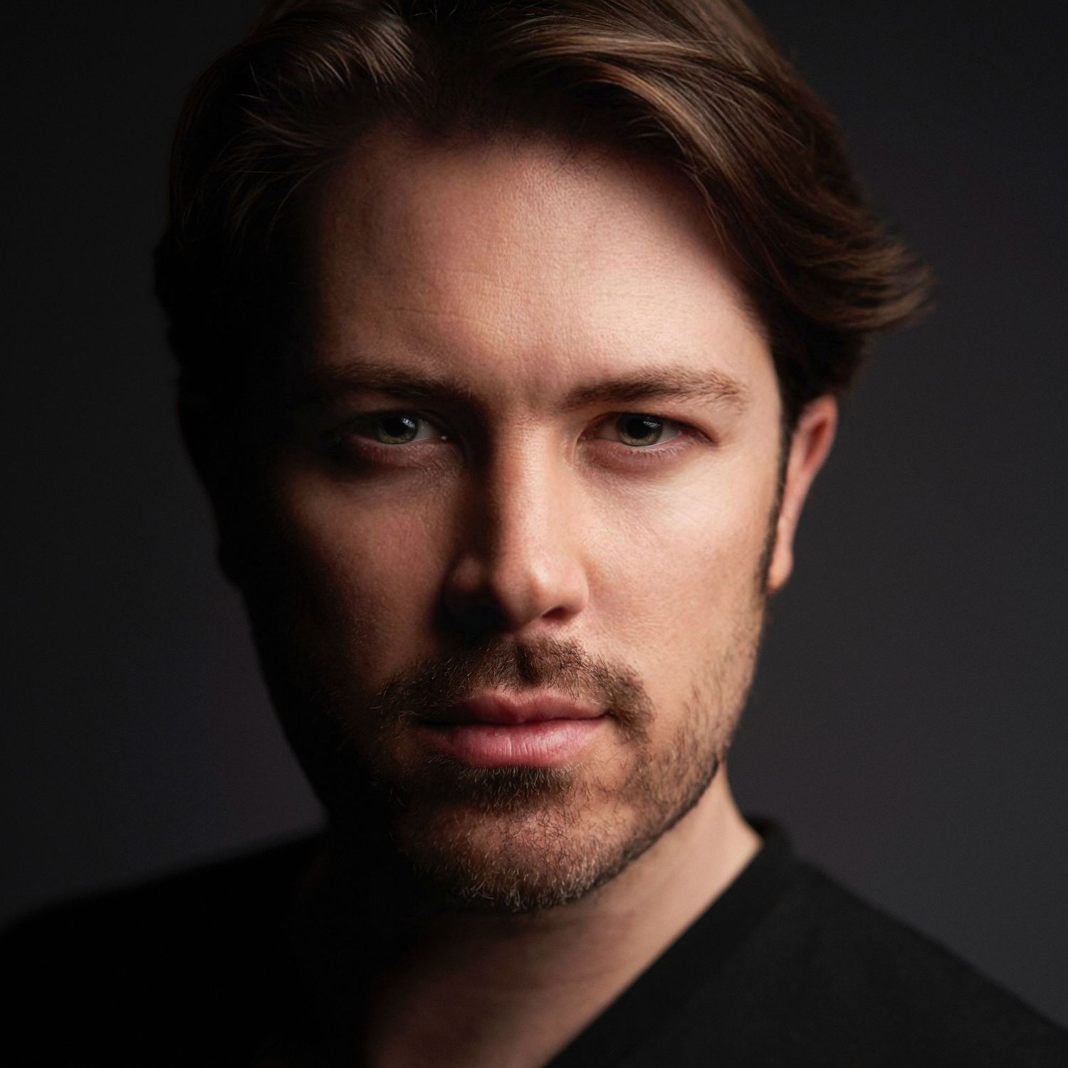 Close up dramatic portrait with moody lighting showing facial features against dark background of Evan Will of Sharko Studios