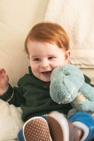 Cheerful moment with a blue plush dinosaur toy while wearing shoes with polka dot soles.