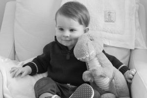 Black and white portrait with a plush toy while wearing a dark sweater.