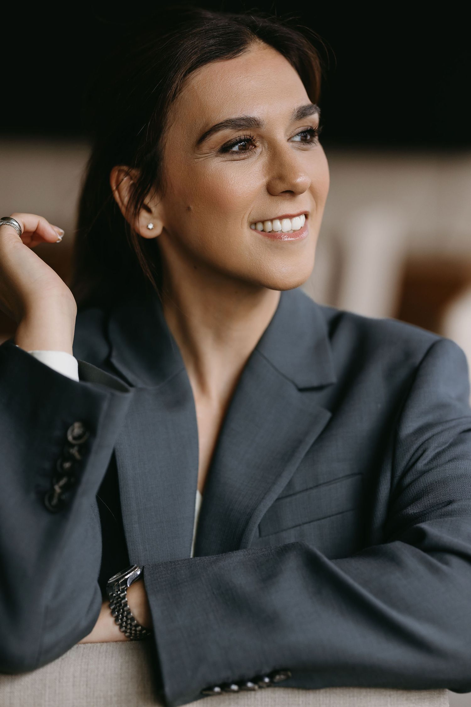 Business portrait showcasing natural smile and professional attire against warm lighting.