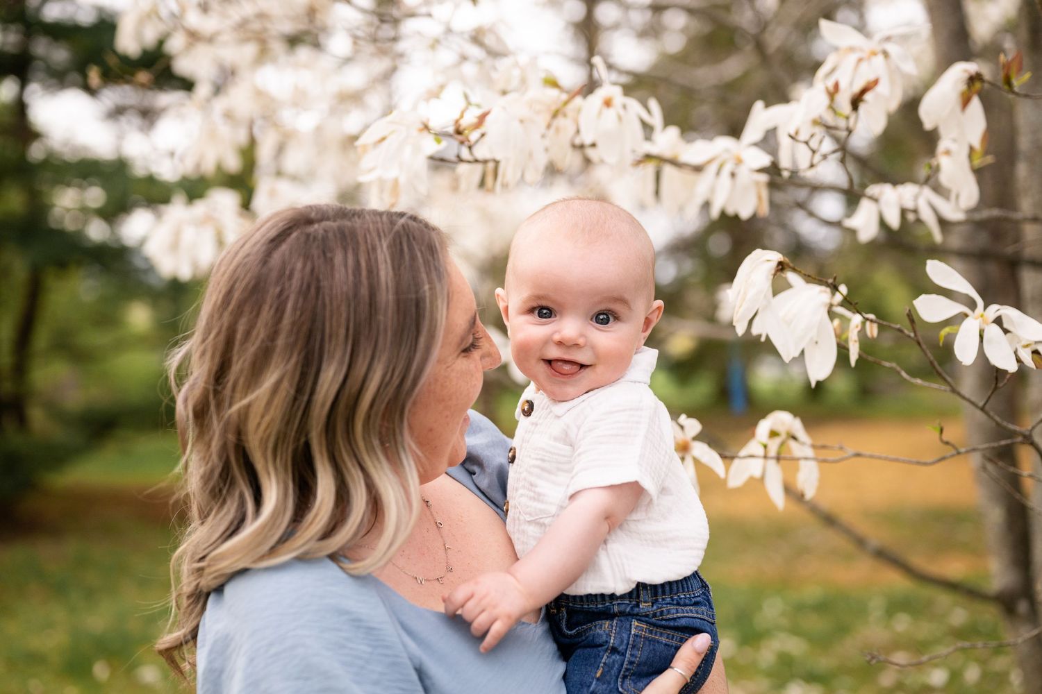 A family shares tender moments under blooming spring magnolia trees in a garden setting.
