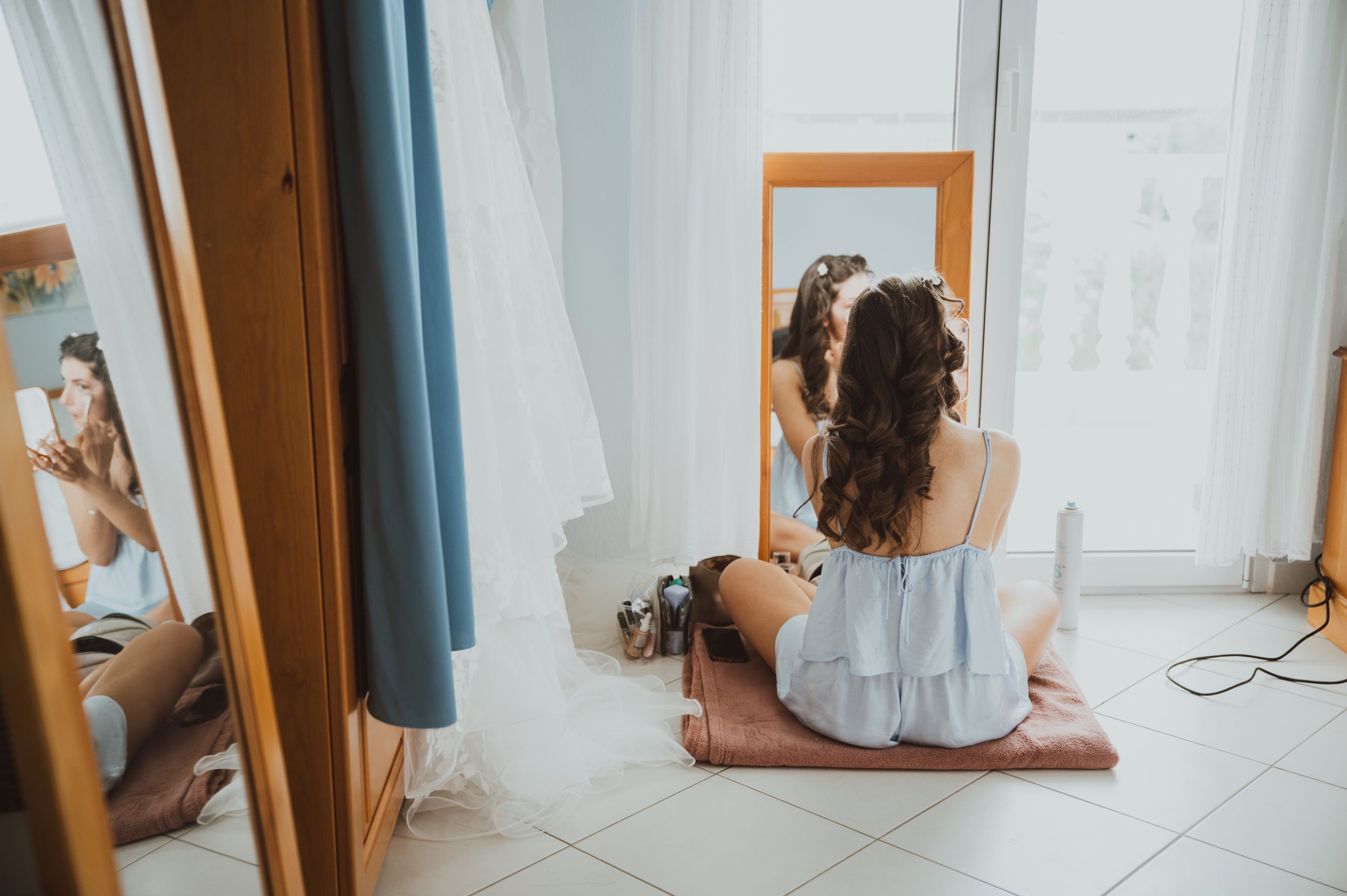 Getting ready scene with wedding dress preparations in a bright, sunlit room.