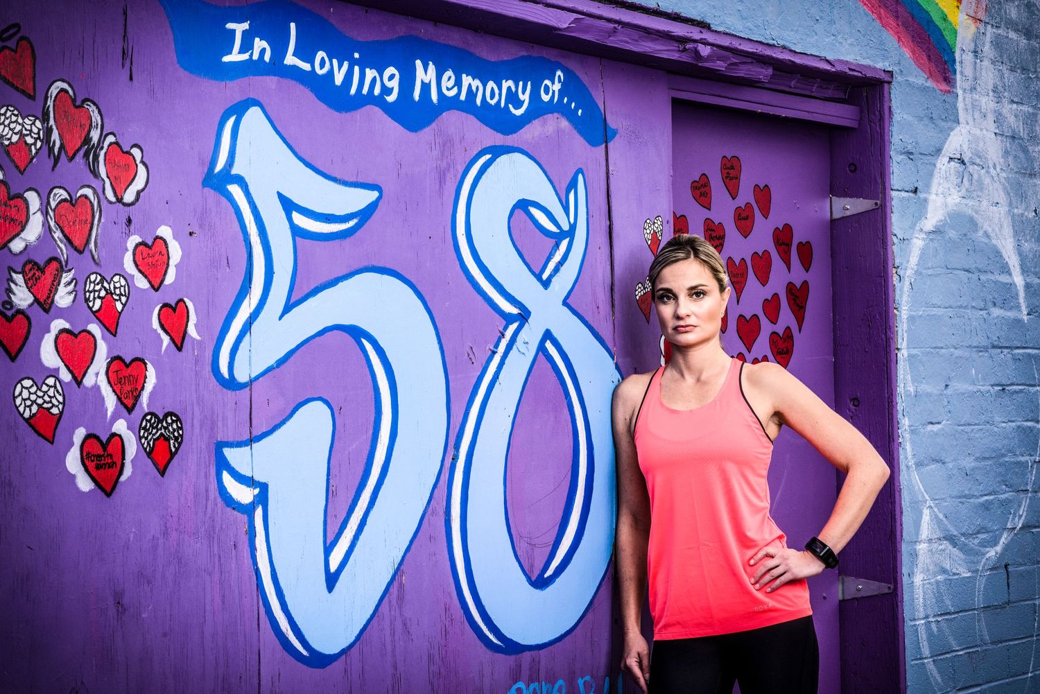 Athlete poses in front of a colorful street art mural with number 58 and hearts painted on purple wall in downtown Las Vegas.