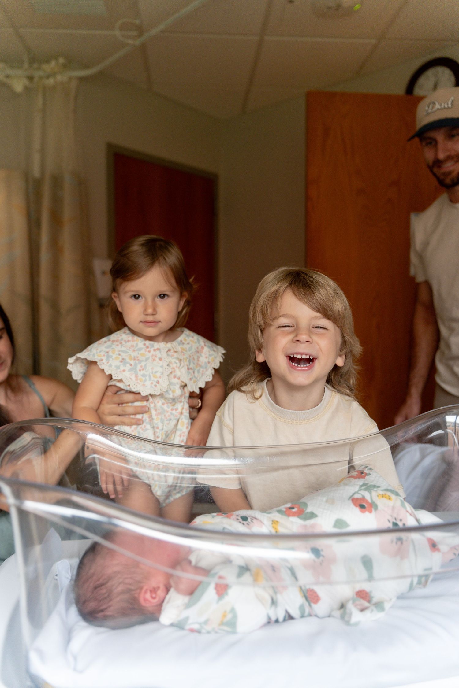 Two young siblings smile proudly over a hospital bassinet holding their newborn baby, with parents visible in background.
UPMC Magee Fresh48