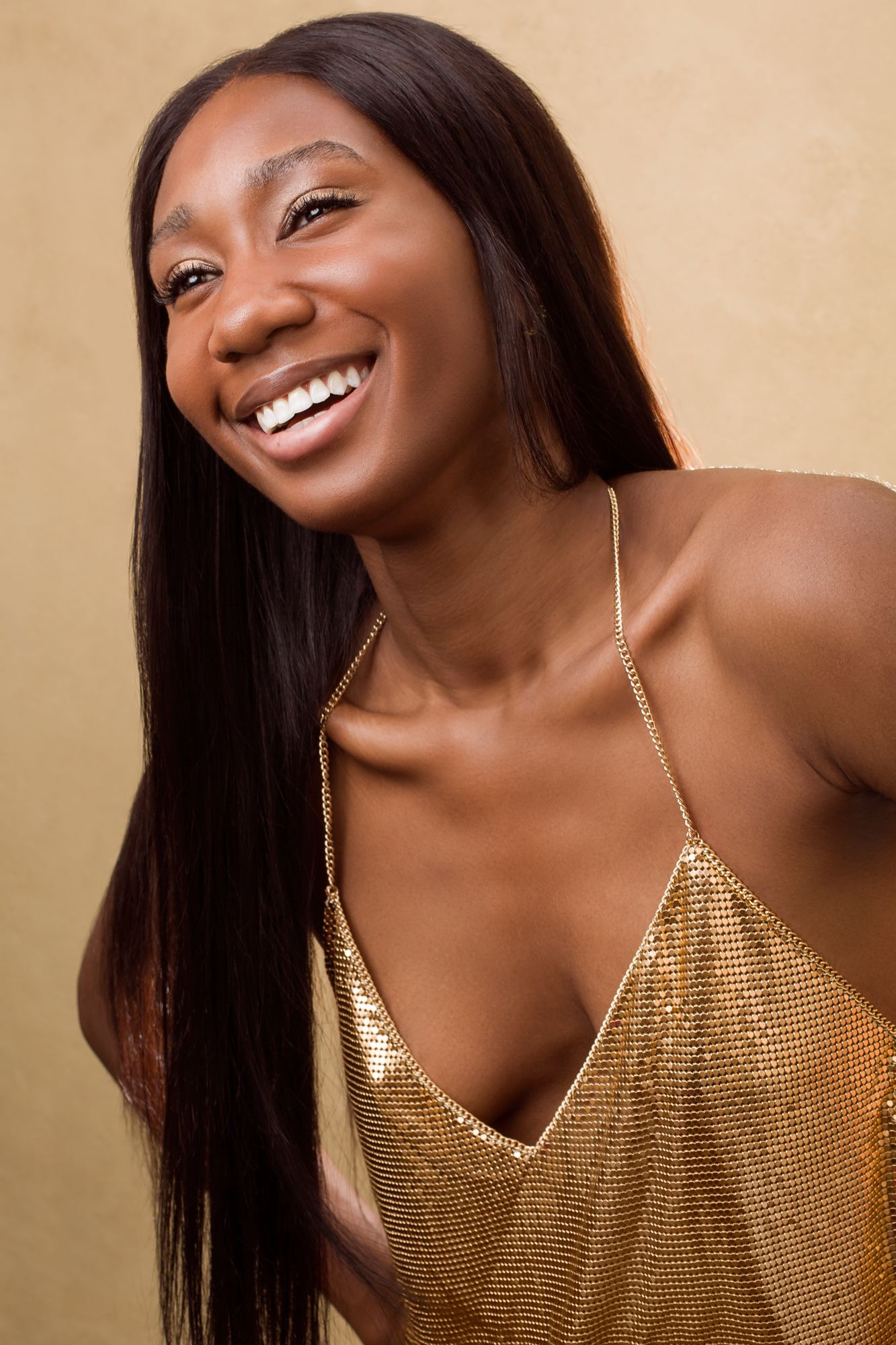 A series of joyful expressions captured in a sequence wearing a sparkling gold top against a neutral background.