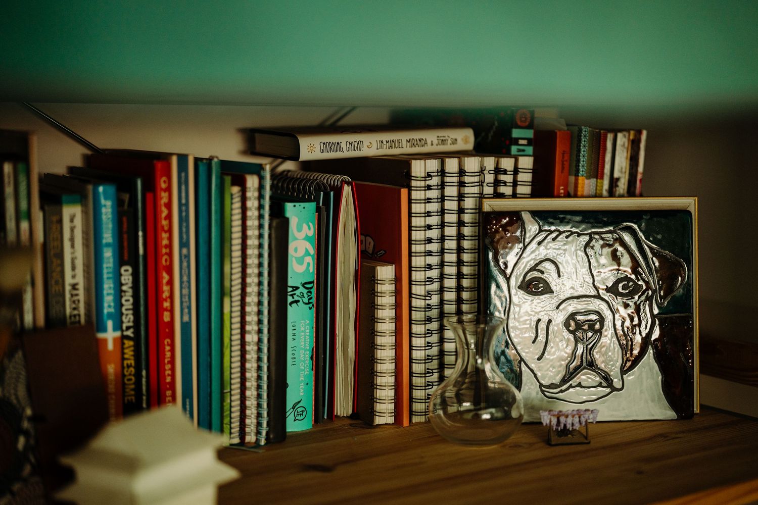 A series of bookshelves with books and decorative artwork displayed against a dark background with green lighting.