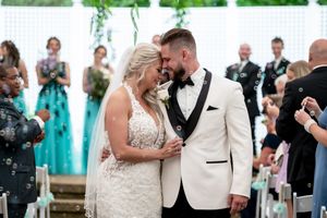 A wedding couple shares intimate moments during their celebration with guests dancing and embracing in the background.