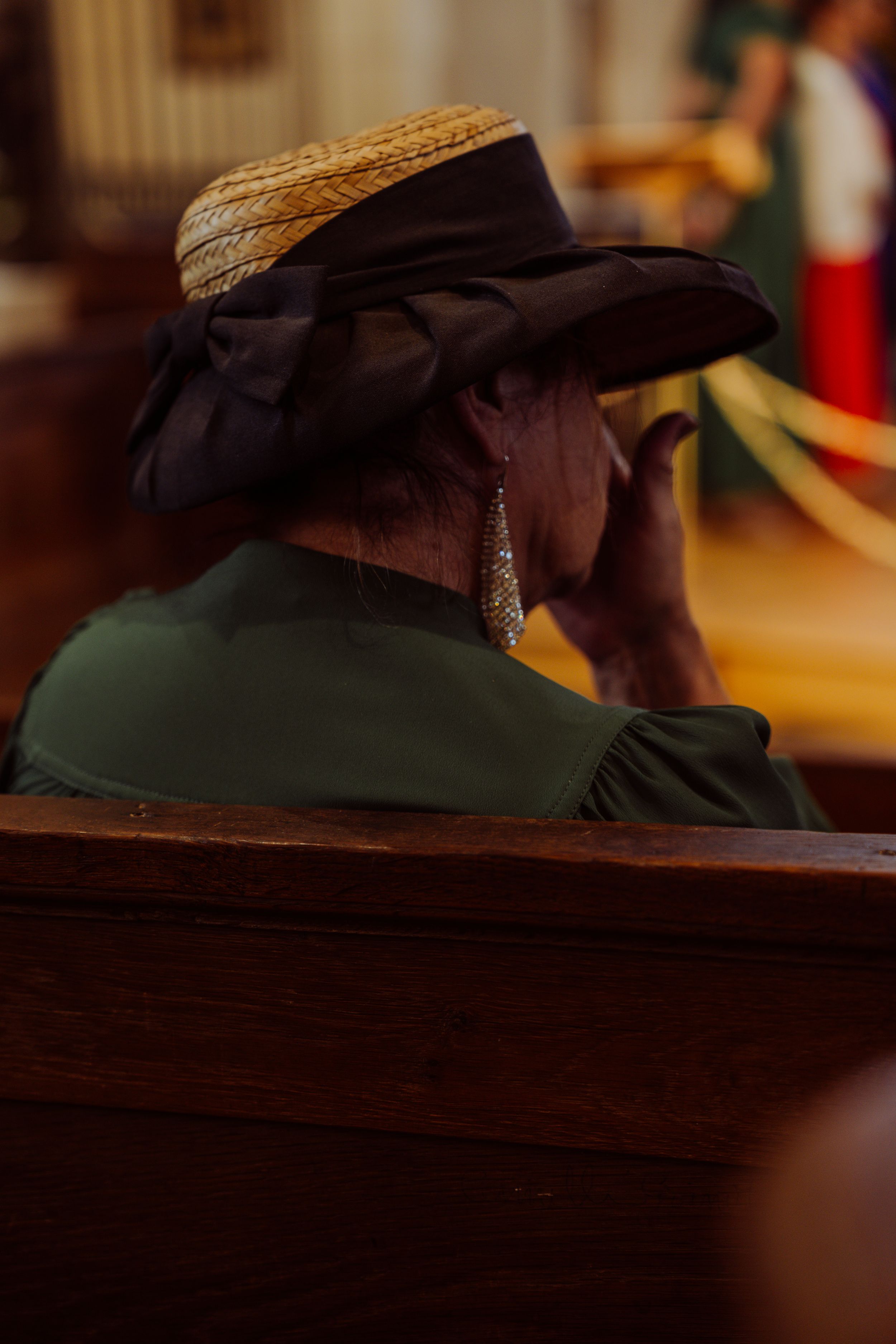 A person wearing a cowboy hat sits in a dimly lit room, captured in a profile view.