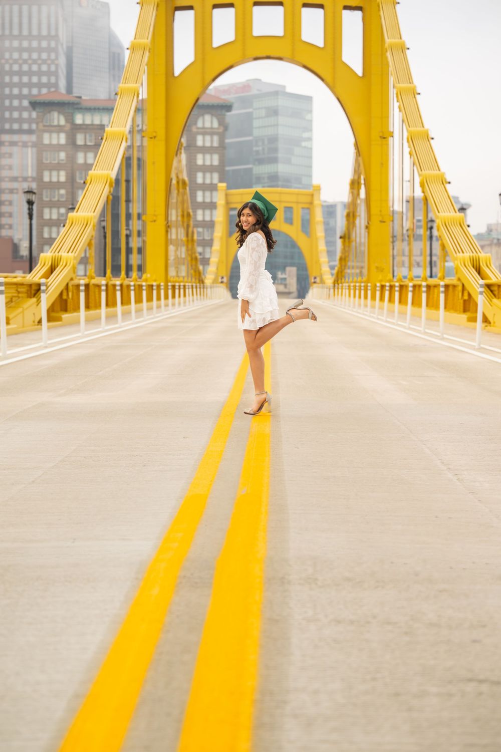 Person walking on bright yellow bridge with geometric arches and urban buildings in background.