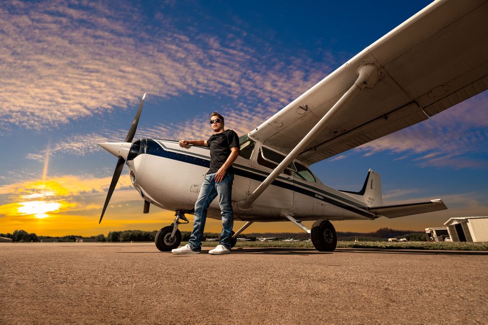 Small aircraft at sunset with person posing next to propeller.