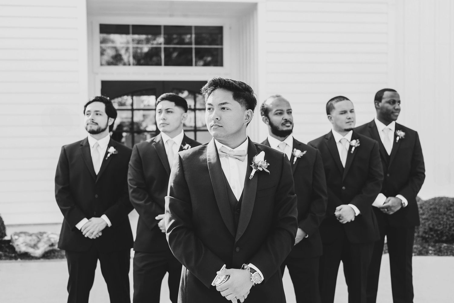 Groom adjusting jacket during black tie wedding portraits