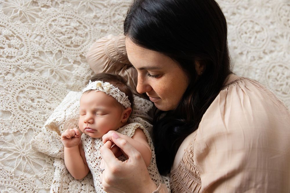A tender moment between parent and baby as they lay together on a soft textured blanket.