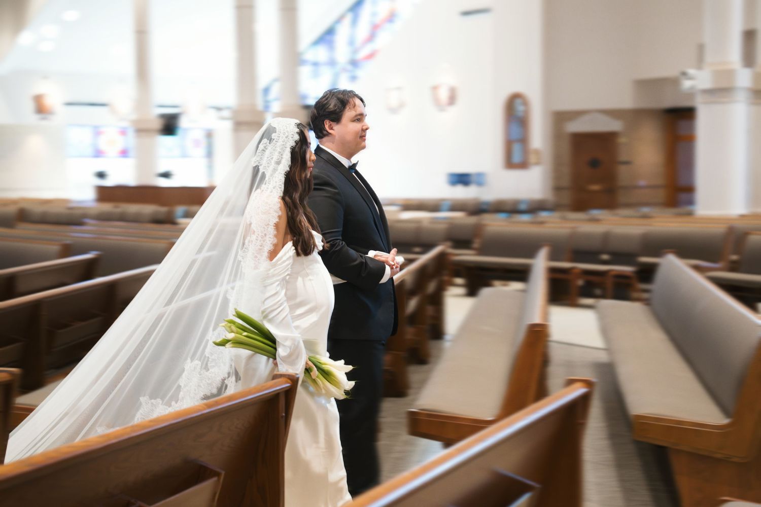 Wedding party walking through church pews with flowing white dress and veil.
