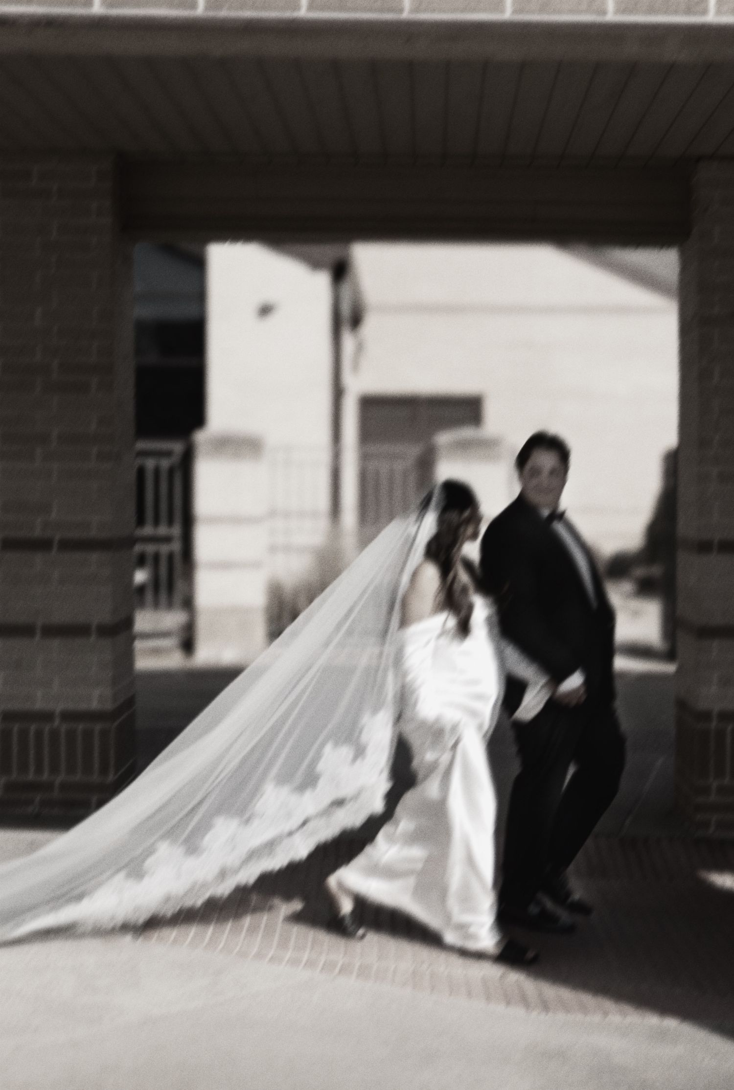A series of artistic black and white wedding photos showing a couple posing near a brick building.