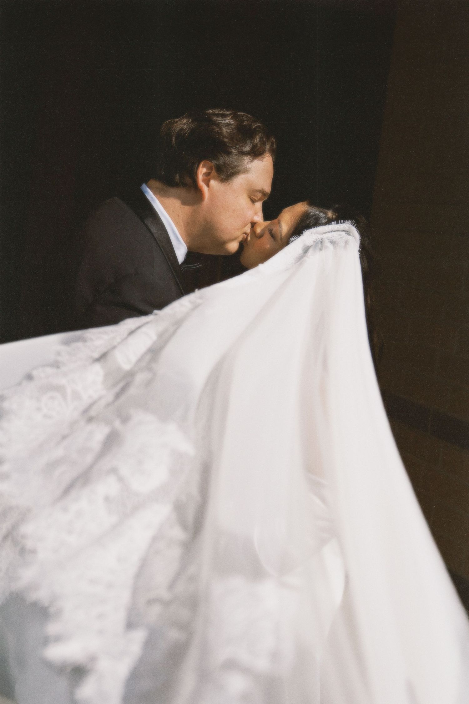 A close-up sequence of a delicate white wedding veil flowing in the breeze against a dark background.