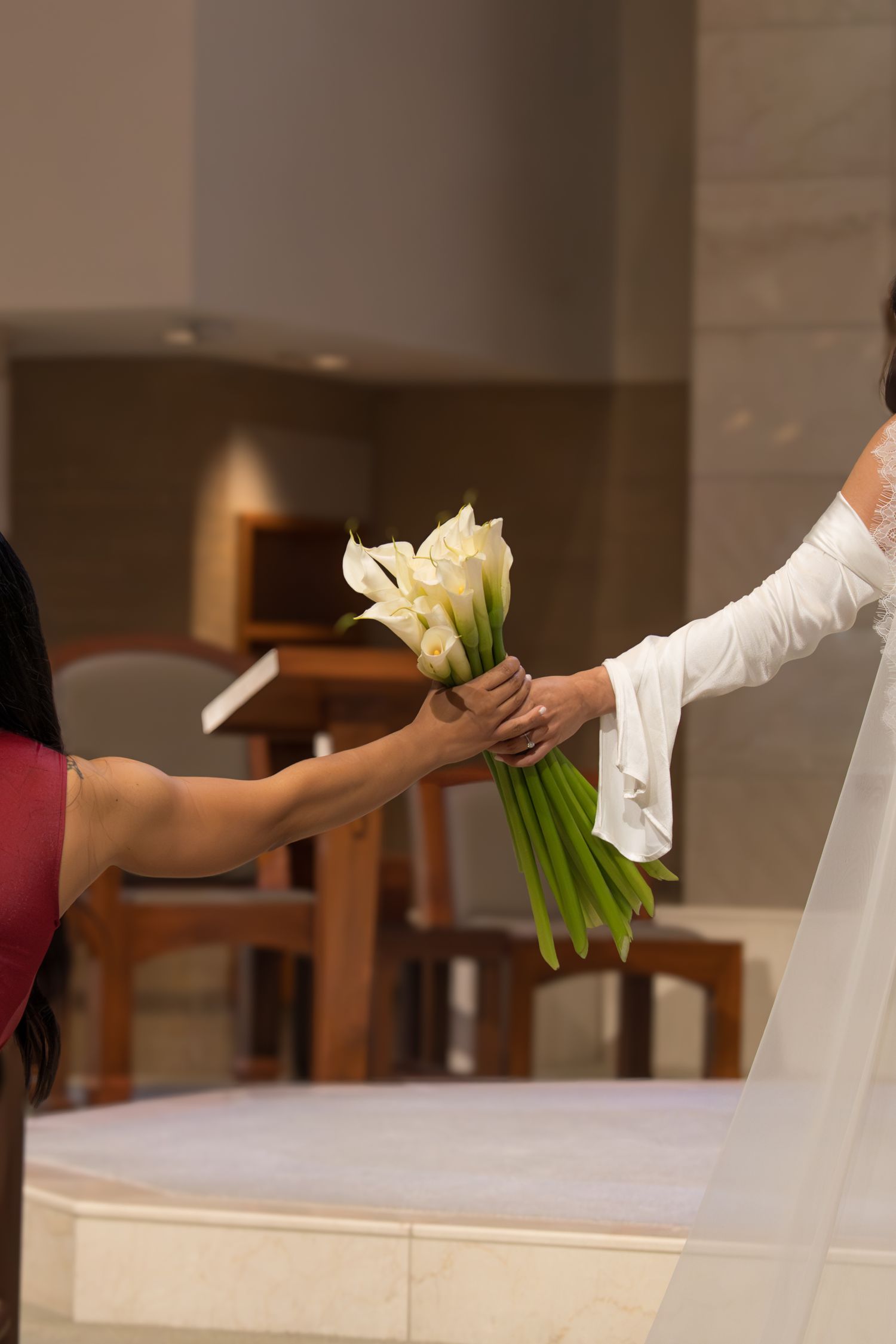 White-clad figures holding delicate white calla lilies in a church setting during a ceremonial procession.