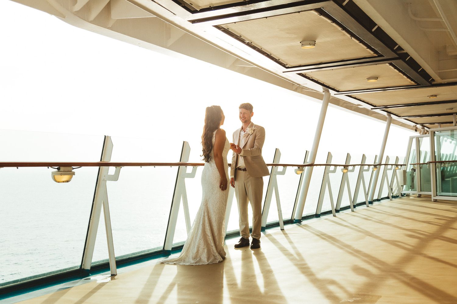 Bride and groom sharing a romantic moment on a cruise ship deck overlooking the ocean.