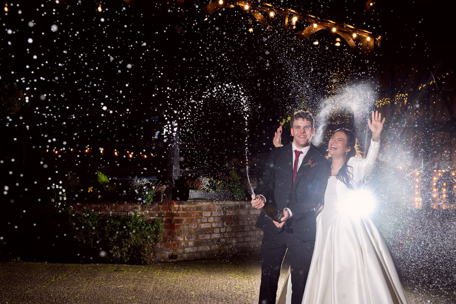 Wedding couple shares a romantic dance under falling snow at night while guests watch and celebrate.