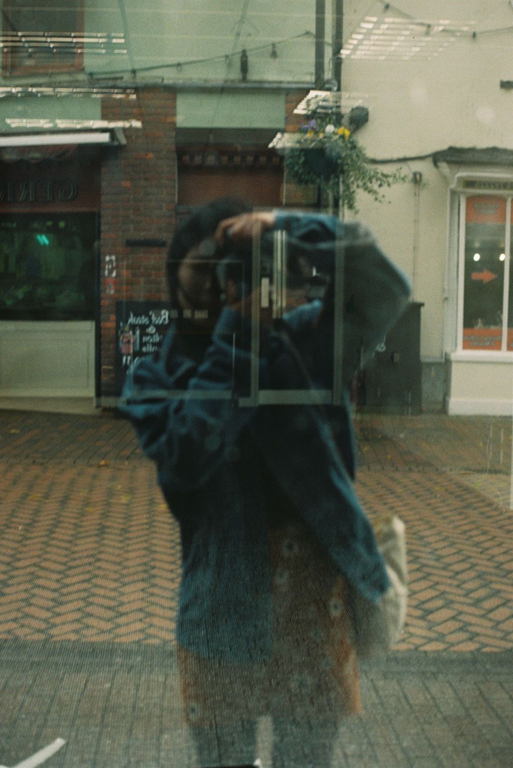 film photograph of a woman captured in the reflection of a shop window.