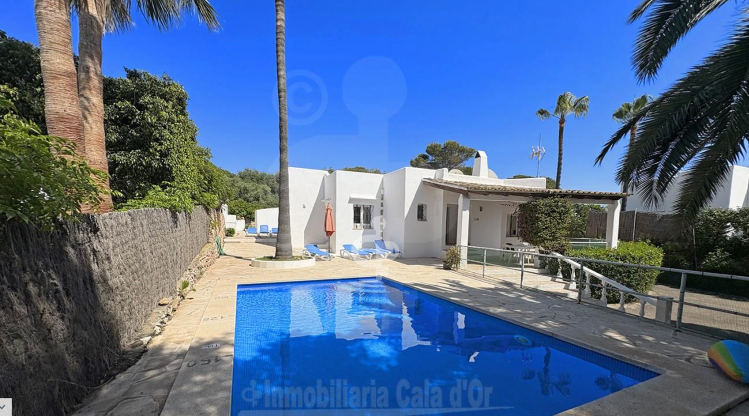 Modern white Mediterranean style house exterior with covered patio and gravel landscaping under bright blue sky.