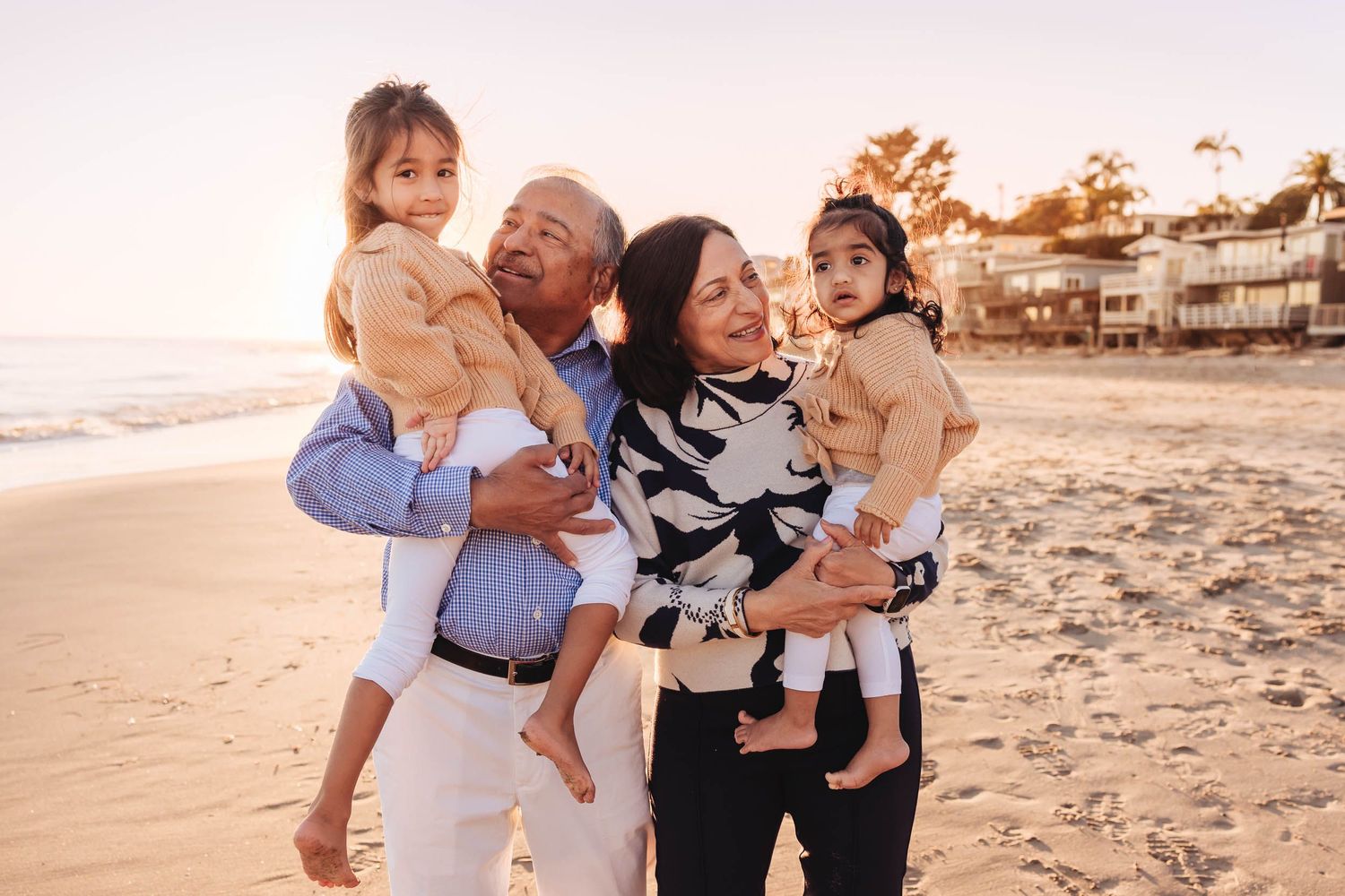 Family enjoying a sunset photoshoot together on a sandy beach with warm golden light.