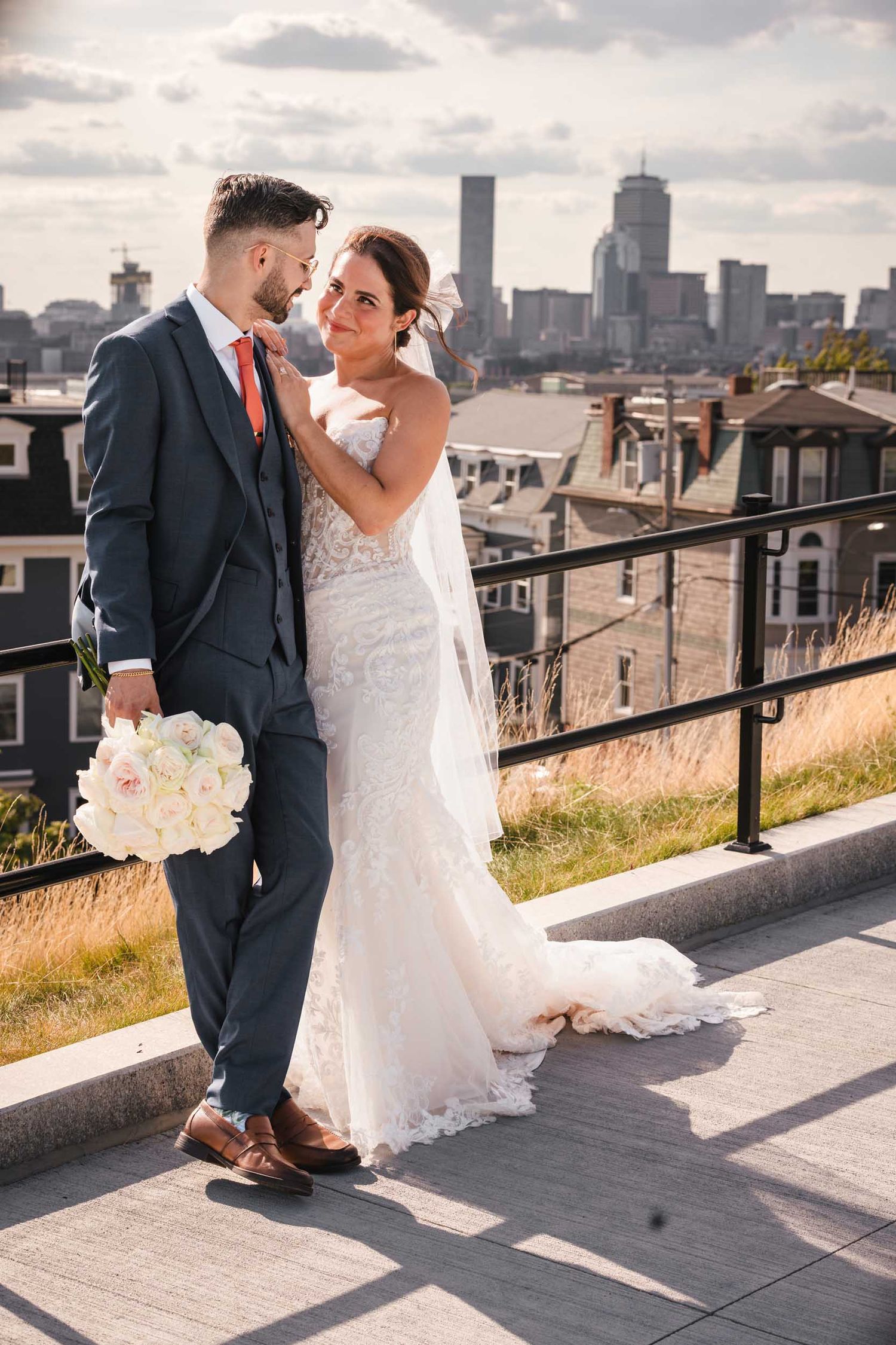 Bride and groom sharing an intimate moment during wedding portraits at Dorchester Heights with the Boston skyline behind them