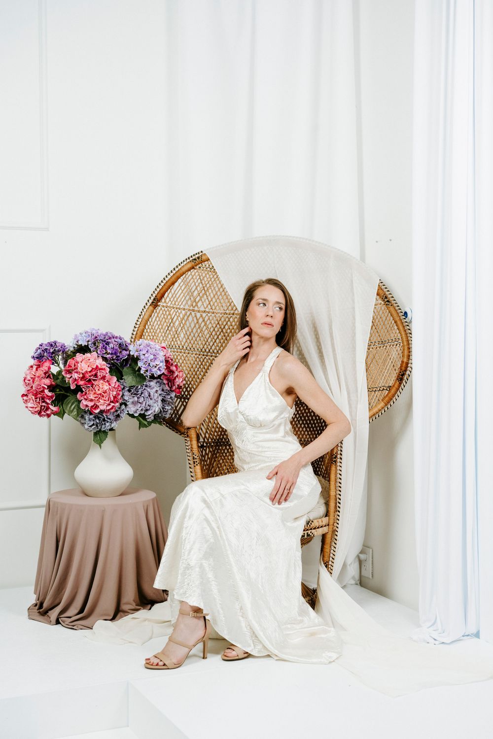 Elegant bridal portrait session with white gown, peacock chair and purple hydrangea arrangements.