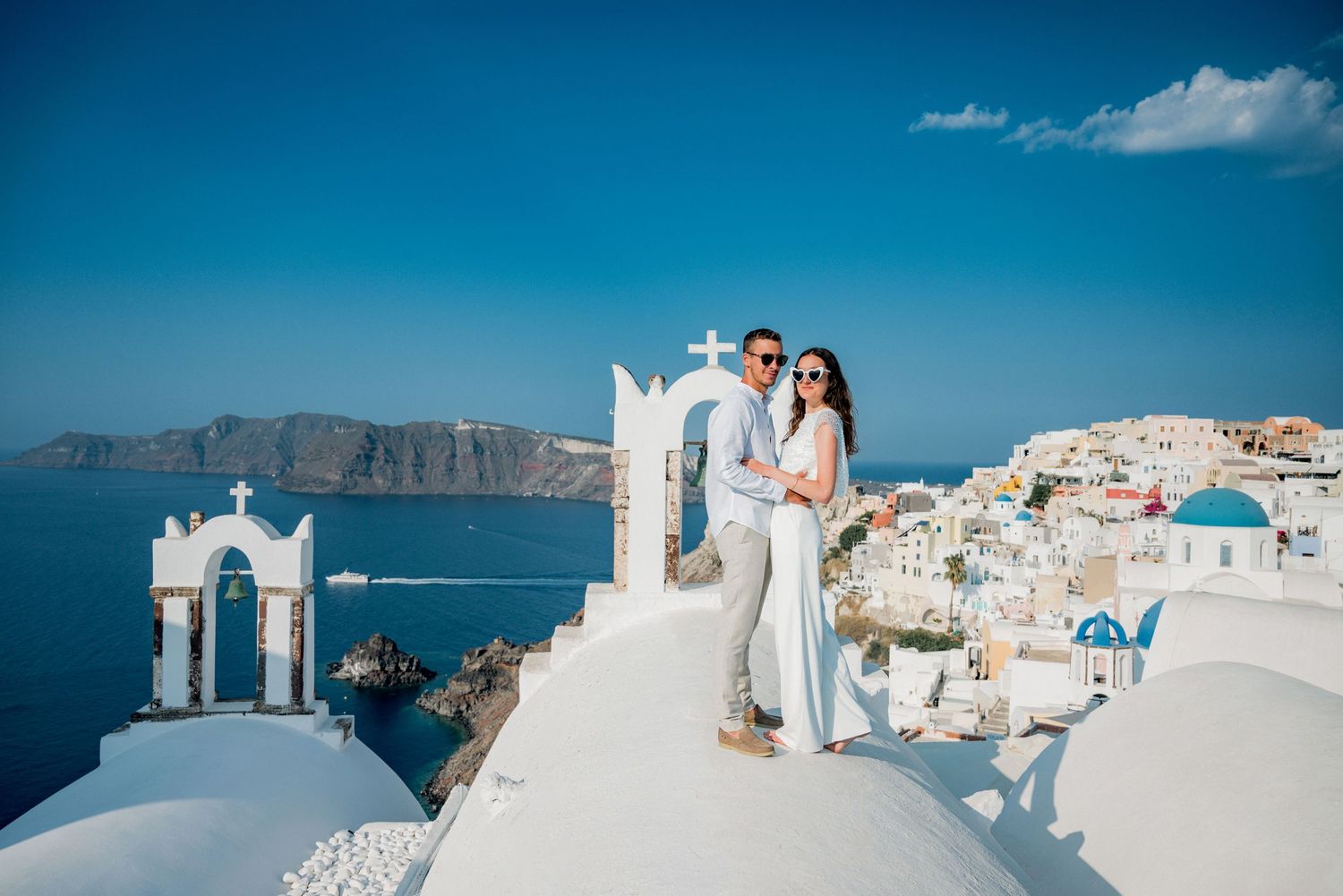 A series of romantic wedding photos captured against the iconic white buildings and blue domes of Santorini, Greece.
