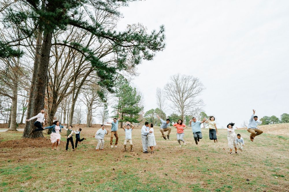 People in colorful outfits walk in a line along a grassy hillside on an overcast spring day.