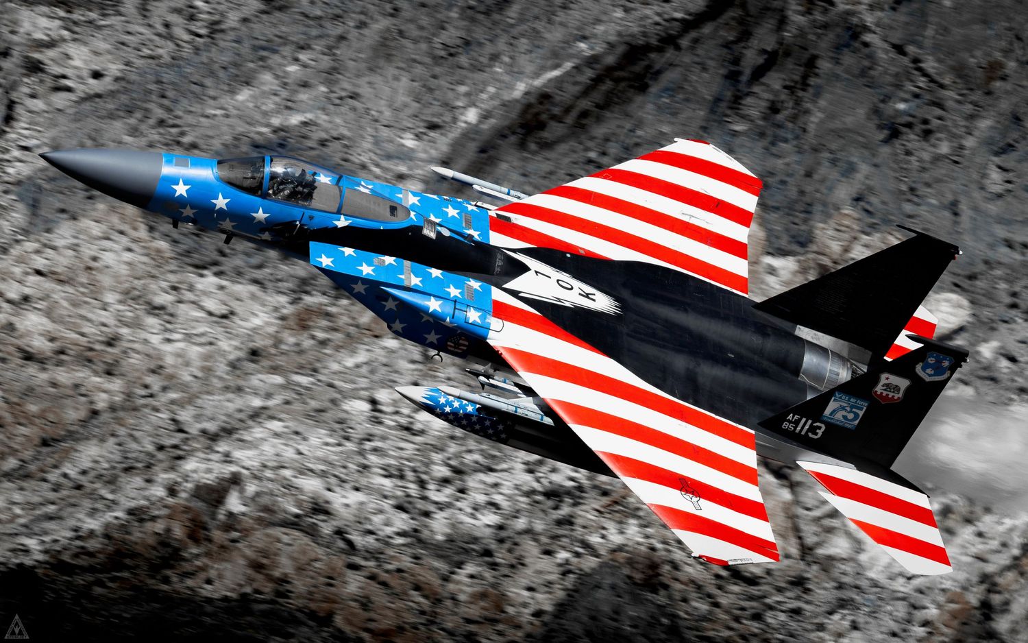 An American Flag painted F-15C Flies through a desert canyon