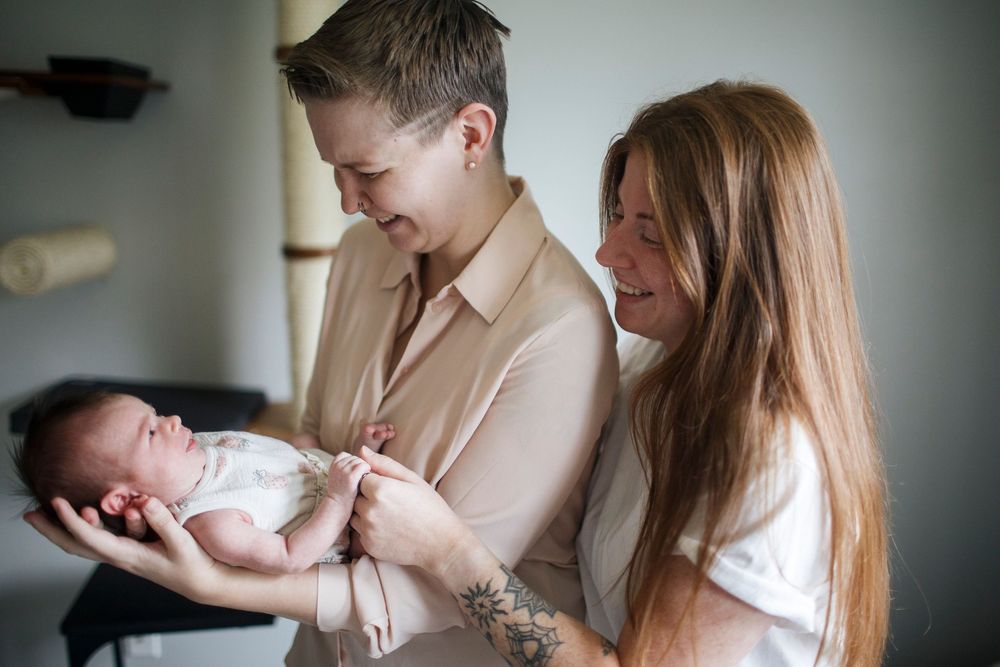 New moms hold their baby at their home newborn photo session in Seattle WA