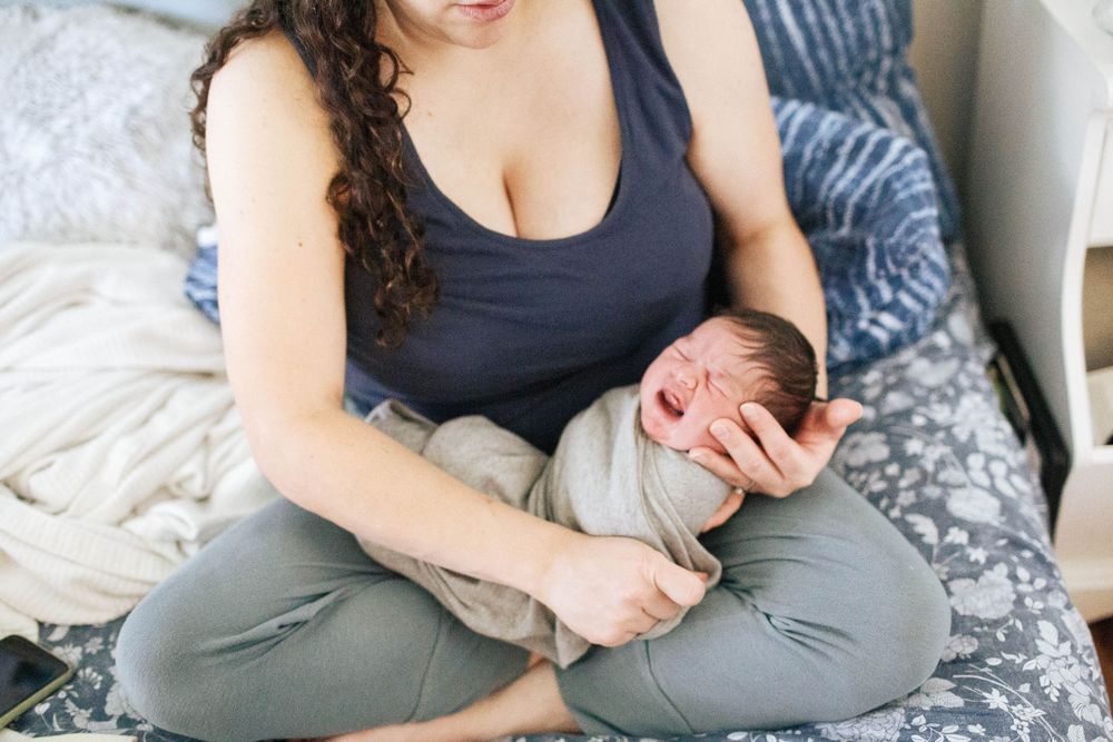 A mother holds her newborn baby at home during a Fresh 48 photo session in Everett WA