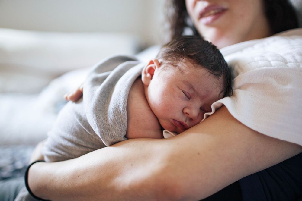 A newborn baby snuggles in her mother's arms during a Fresh 48 session in Seattle WA