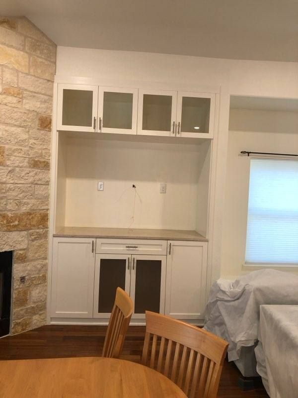 Built-in white cabinet unit with frosted glass doors and stone accent wall in a modern living room interior.