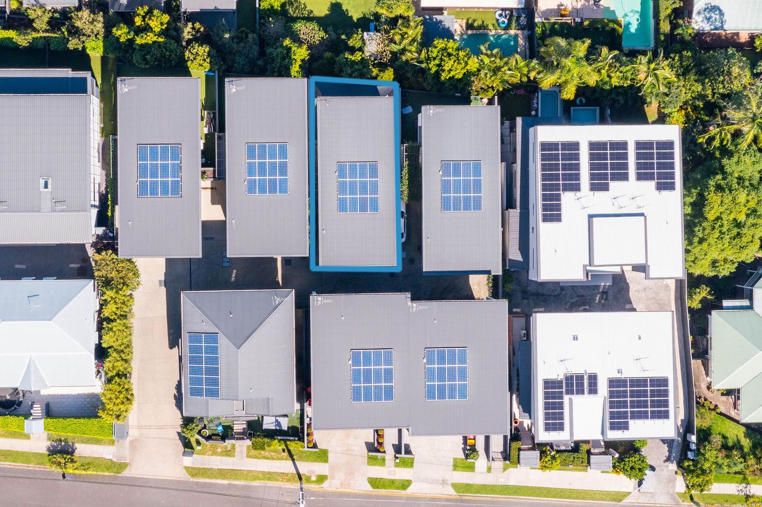 Top-down aerial view of suburban homes with solar panels installed on rooftops in an Australian neighborhood.