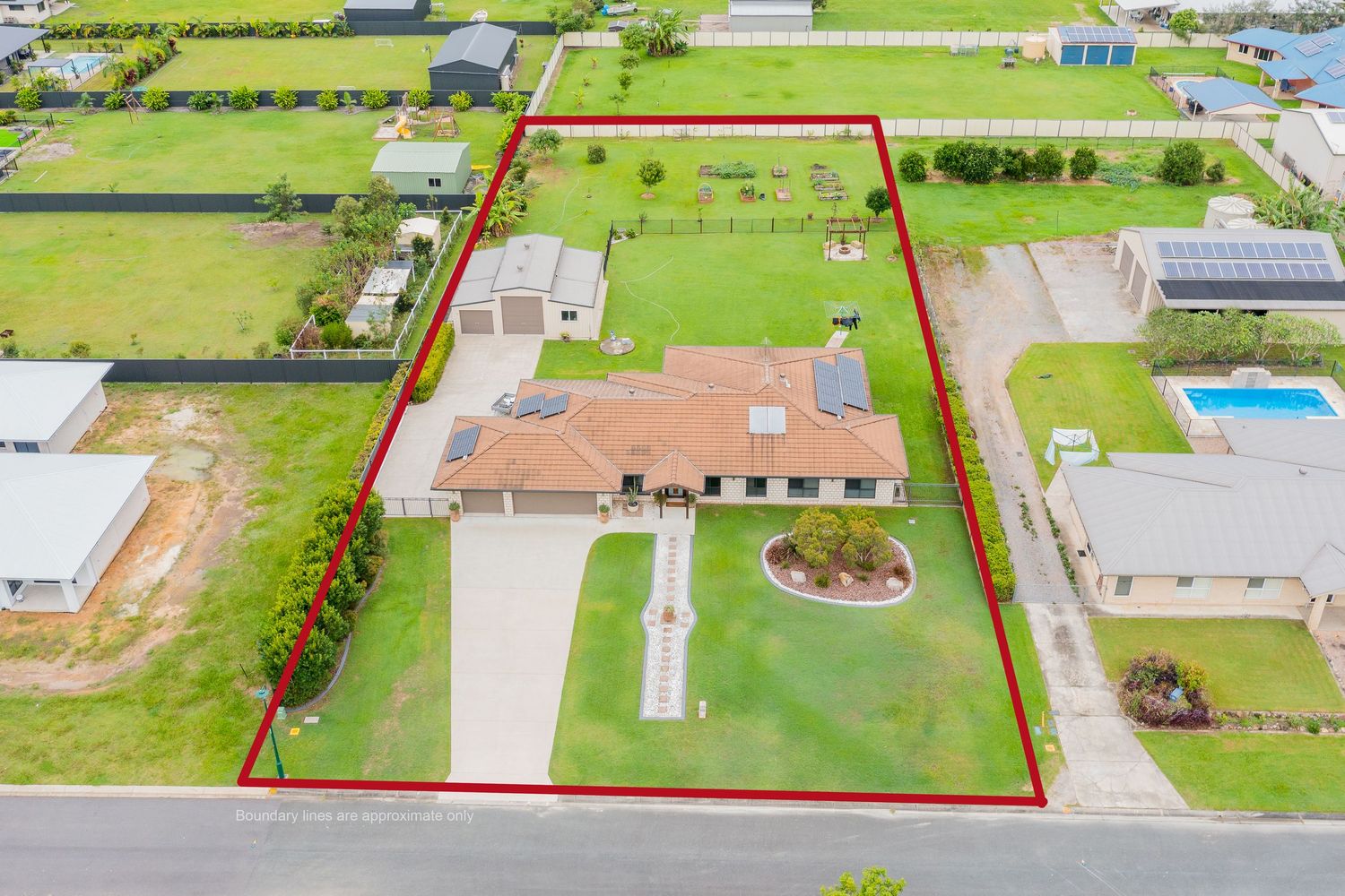 Aerial view of a large rural property outlined in red with a brick home, pool, and spacious green lawns.