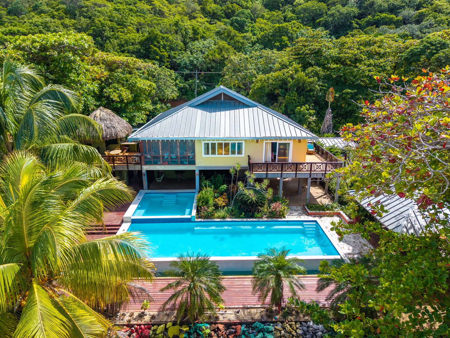 Panoramic view of multiple swimming pools and modern homes nestled among tropical greenery.