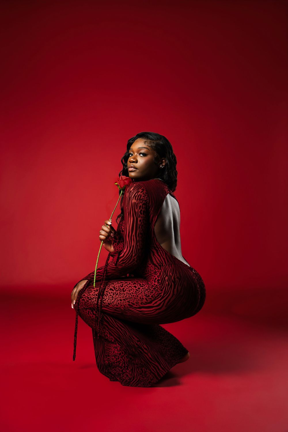 Artistic portrait series against deep red background shows figure in dramatic poses with flowing red braided hair.