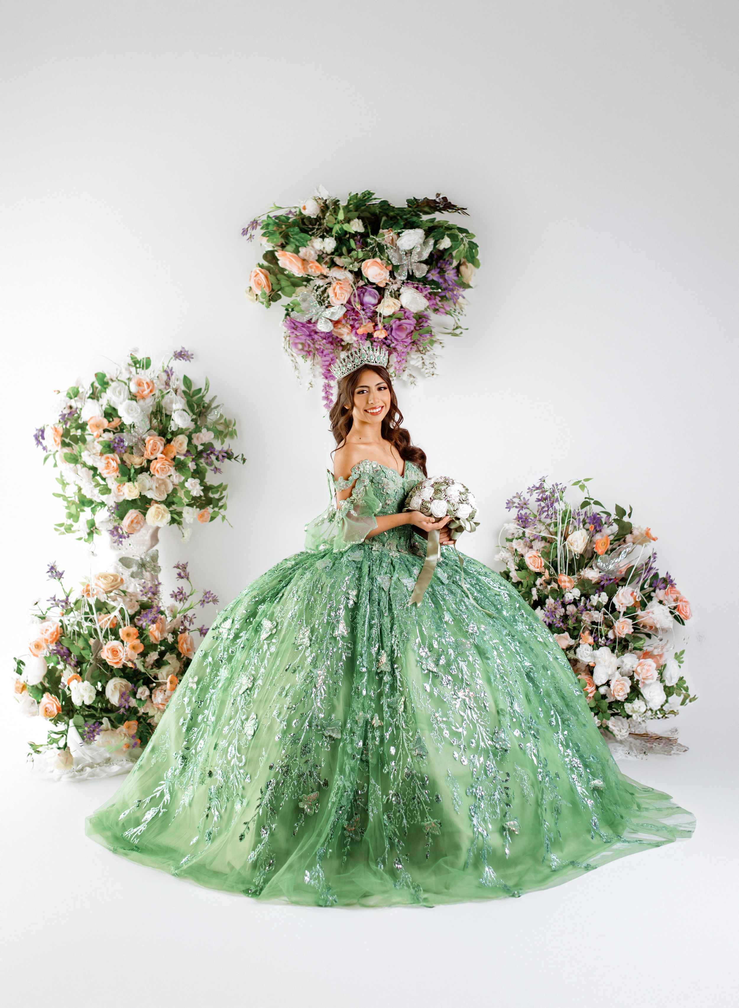 A stunning mint green ball gown with sparkles and floral decorations against a white backdrop creates a dreamy scene.