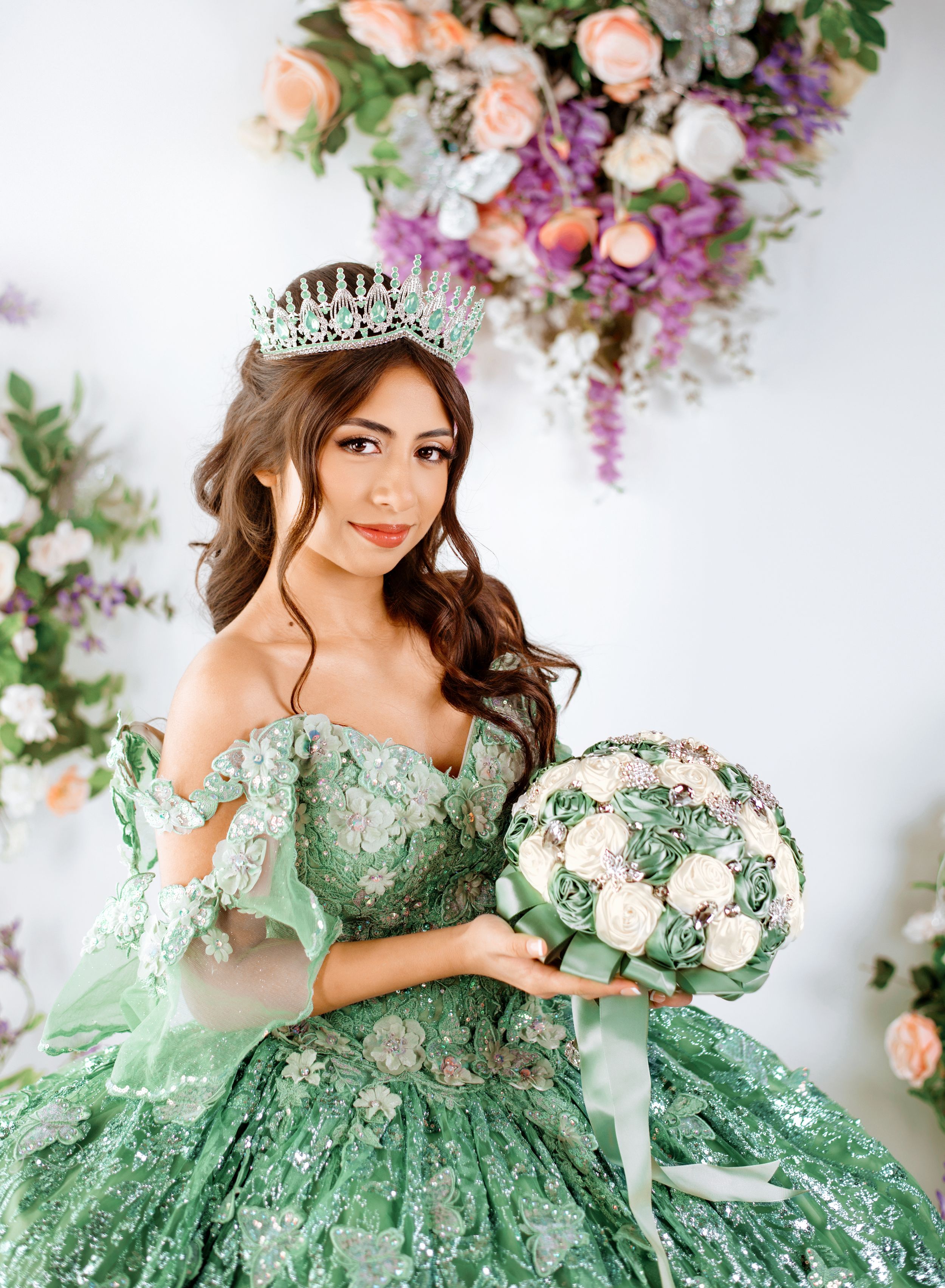 A stunning mint green ball gown with lace details is showcased among floral decorations and soft lighting.